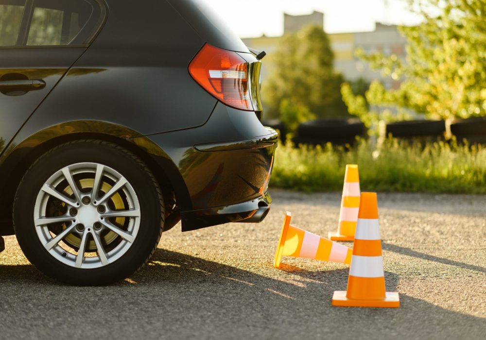 Car and orange traffic cones, lesson in driving school concept, nobody. Teaching to drive vehicle theme. Driver's license education